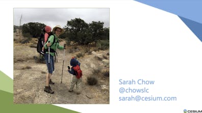 A photo of a woman in hiking gear with a baby in a pack on her back and a young child standing next to her, in a rocky desert landscape